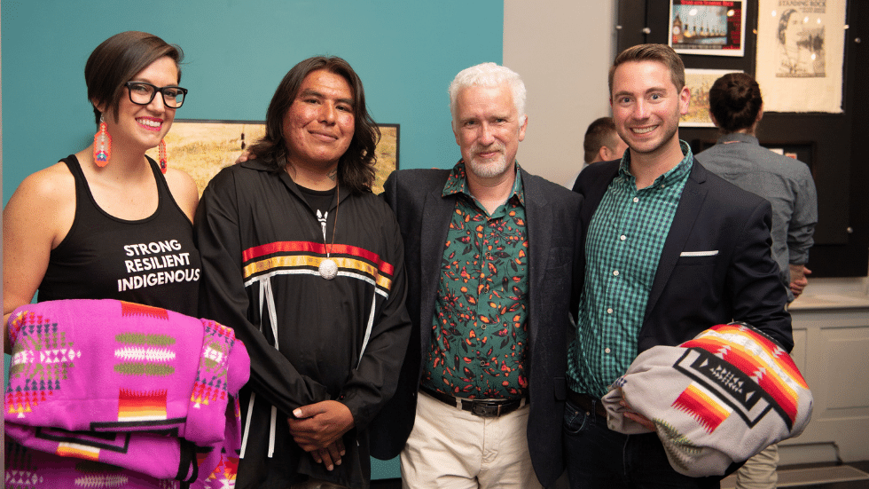 Four people posing for a photo, including the two curators, the deputy director, and featured artist.