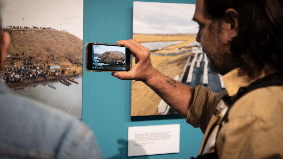 Guest taking photo on his phone of photos on display in the exhibit. 