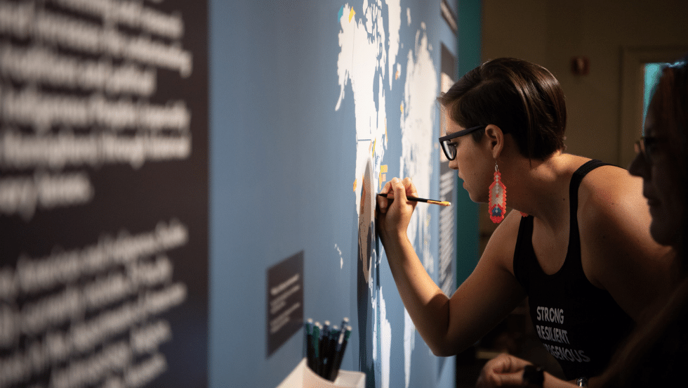 Photo of curator adding to the interactive map wall in the exhibit.