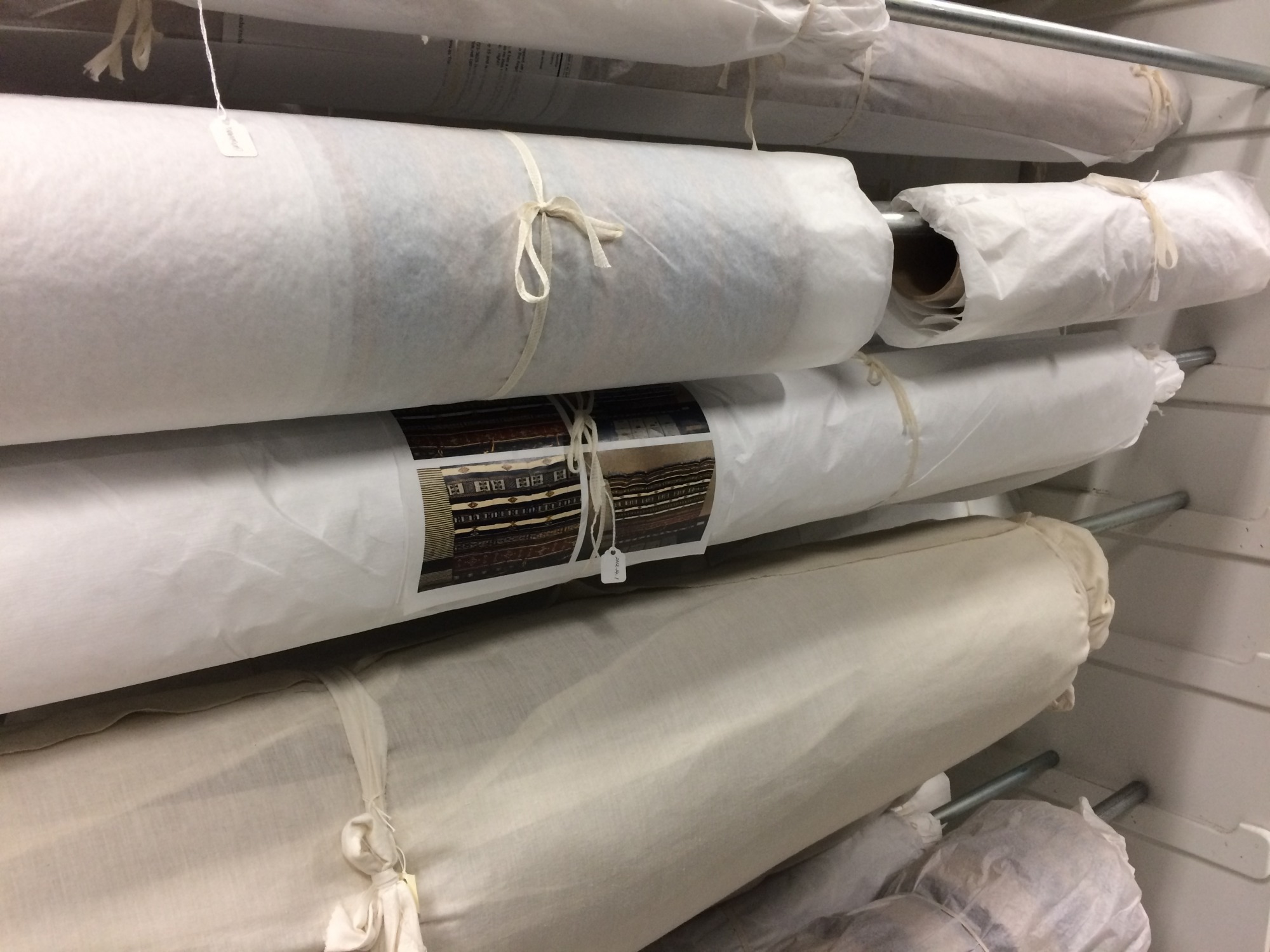 Rolled textile in the Museum storage, wrapped in tissue paper and labeled. 