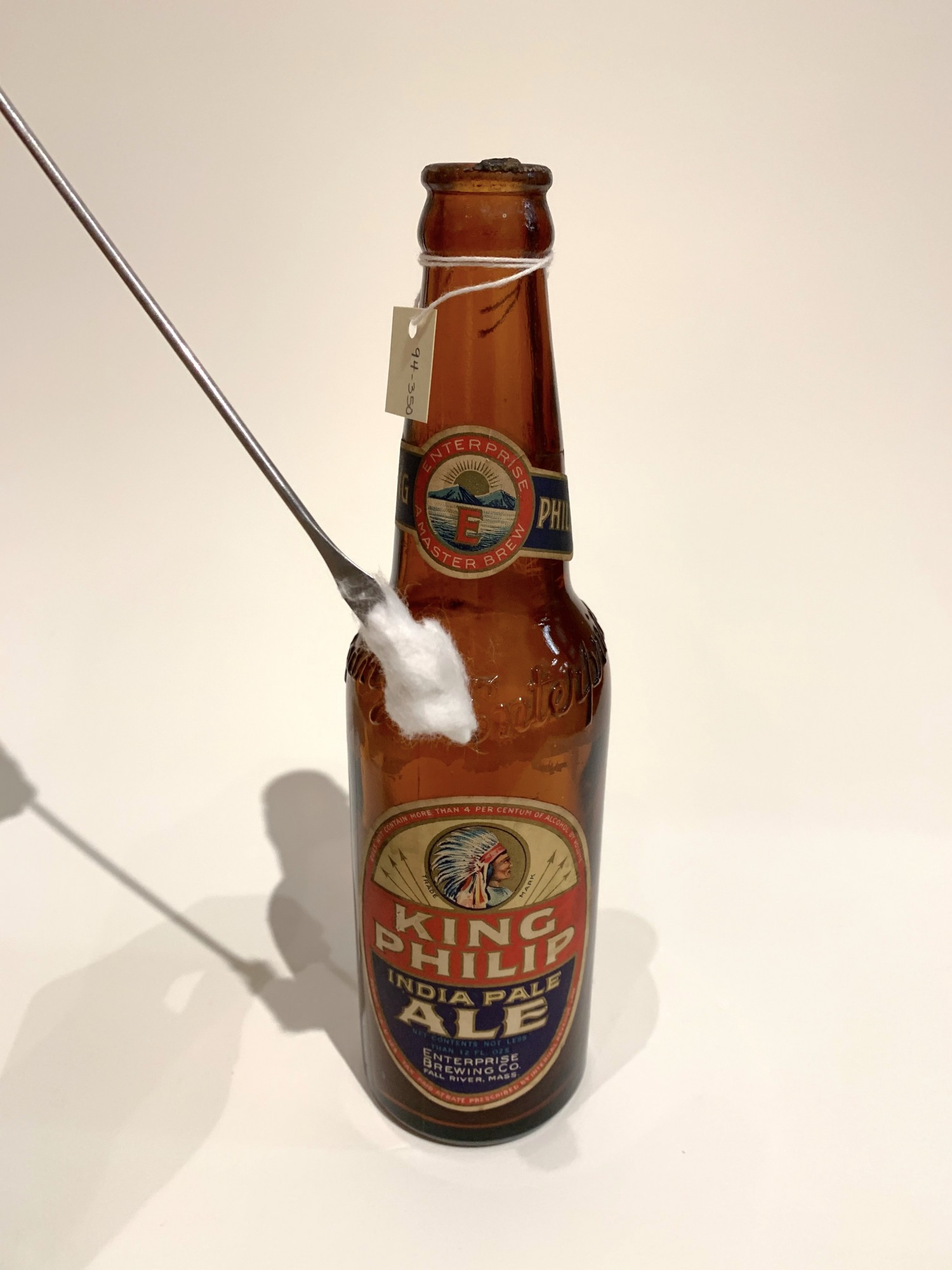 Photo of an antique glass beer bottle being cleaned with a cotton q-tip.