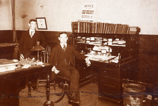 Antique photo of two men in an office; the seated man is Rudolf Haffenreffer. 