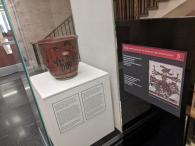 Photo of tall glass case in the Rockefeller Library displaying a large painted urn.